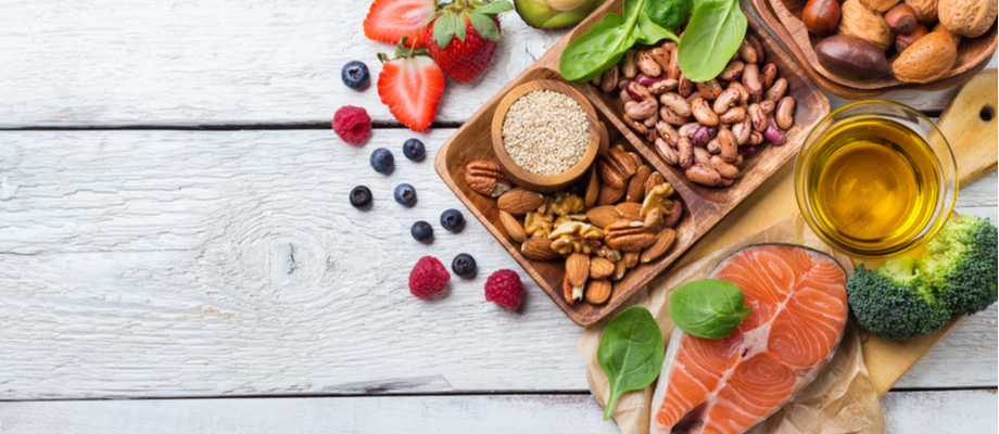 Mesa de madera con alimentos saludables: frutas, semillas, vegetales.