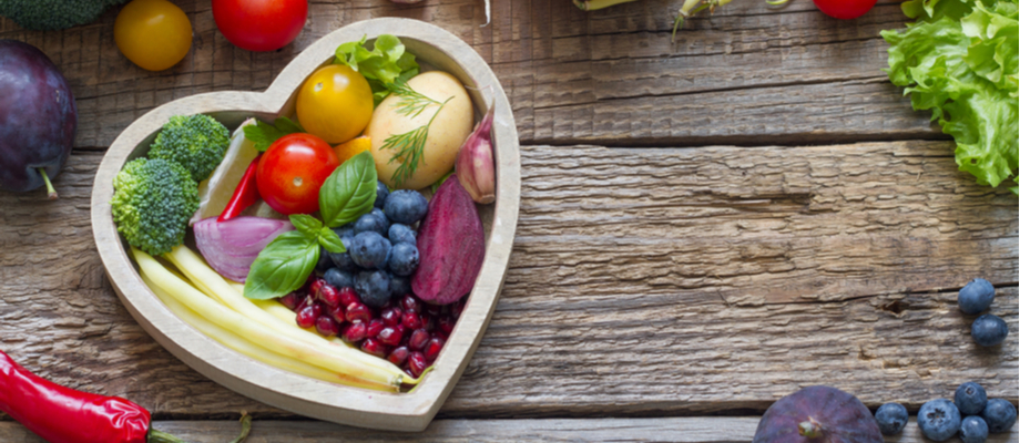 Plato en forma de corazón con comida saludables, frutas y vegetales.